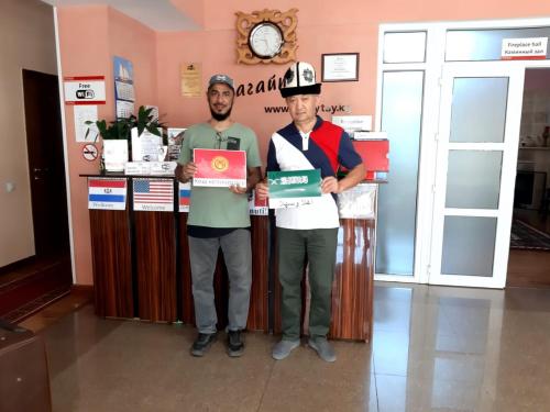 two men standing in front of a counter holding a sign at Tagaytay Karakol Hotel in Karakol