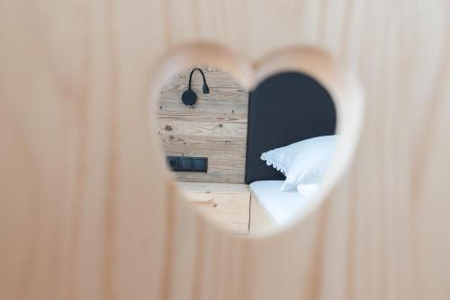 a room with a bed through a heart shaped mirror at MESNERHOF CHALET - Ruhe, Rückzug & Südtiroler Charme mit kostenlosem Parken in der Tiefgarage in Bressanone