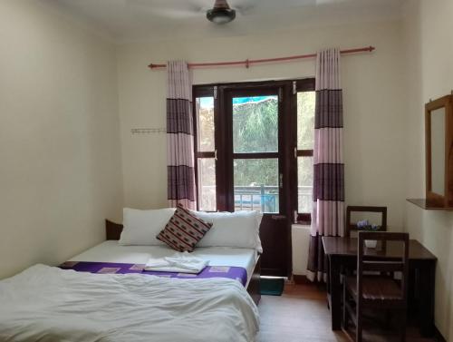 a bedroom with a bed and a window at Hotel small town guest house in Bandipur