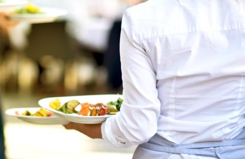 a chef holding a plate of food on a table at Garner Hotel Oberhausen in Oberhausen