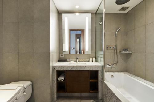 a bathroom with a tub and a sink and a mirror at LOTTE City Hotel Gimpo Airport in Seoul