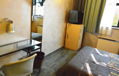 a room with a bed and a desk and a television at Hotel Balbo in Turin