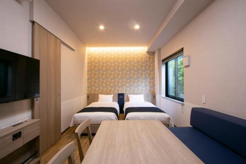a room with three beds and a table and a tv at Minn Kasai in Tokyo