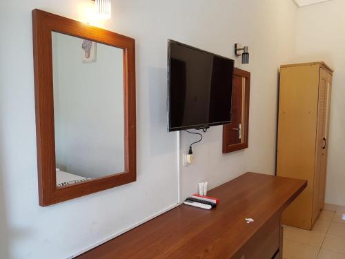 een kamer met een tv aan de muur en een houten tafel bij Kost & Homestay 911 in Mataram