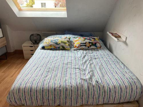 a bedroom with a bed with a striped comforter and a window at Ty Cèdre in Crozon