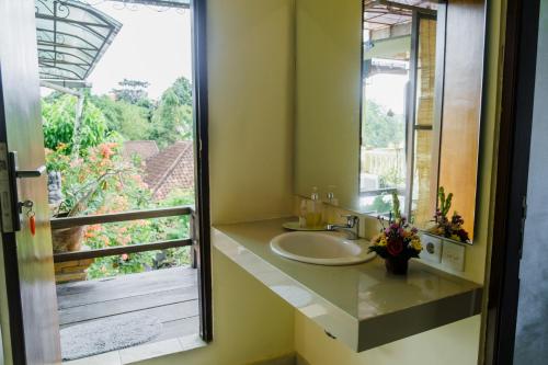 La salle de bains est pourvue d'un lavabo et d'une grande fenêtre. dans l'établissement Desak Putu Putra Home Stay, à Ubud