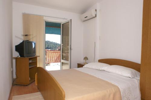 1 dormitorio con cama, TV y balcón en Apartments by the sea Brna, Korcula - 4333, en Brna