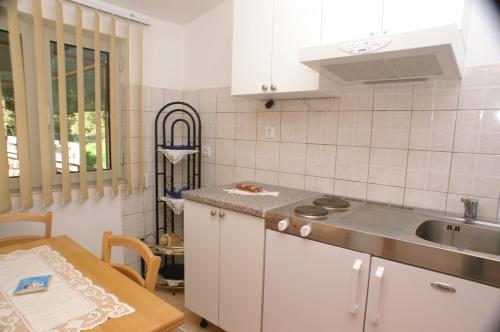 a kitchen with white cabinets and a sink and a table at Apartments by the sea Brna, Korcula - 4333 in Brna