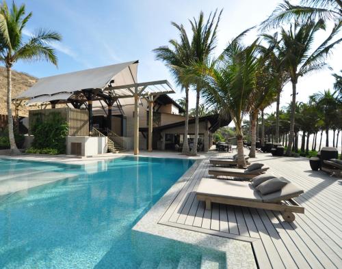 a swimming pool with lounge chairs and palm trees at Arennas Mancora in Máncora