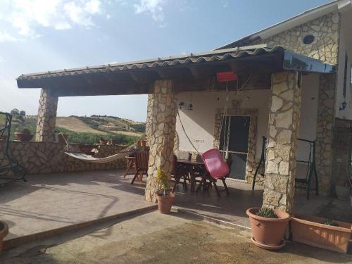 eine Terrasse eines Hauses mit einem Tisch und Stühlen in der Unterkunft Villetta Torre Salsa in Siculiana