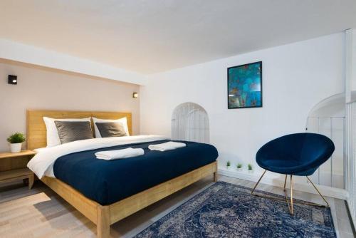 1 dormitorio con 1 cama grande y 1 silla azul en Musrara #5, en Jerusalén