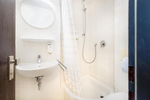 ein weißes Bad mit einer Dusche und einem Waschbecken in der Unterkunft Novum Hotel Leonet Köln Altstadt in Köln