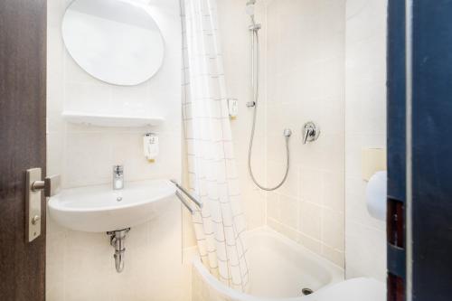 a white bathroom with a shower and a sink at Novum Hotel Leonet Köln Altstadt in Cologne