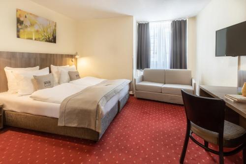 a hotel room with a large bed and a desk at Hotel Leonet in Cologne