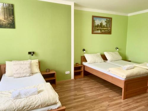 two beds in a room with green walls and wooden floors at Penzion Kundratice in Kundratice