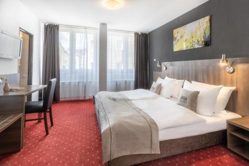 a hotel room with a large bed and a desk at Hotel Leonet in Cologne