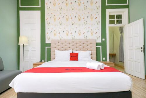 1 dormitorio con cama blanca grande y almohada roja en RedDoorz Premium near RS Pondok Indah La Maison en Yakarta