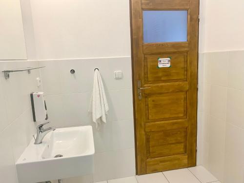 a bathroom with a wooden door next to a sink at Penzion Kundratice in Kundratice