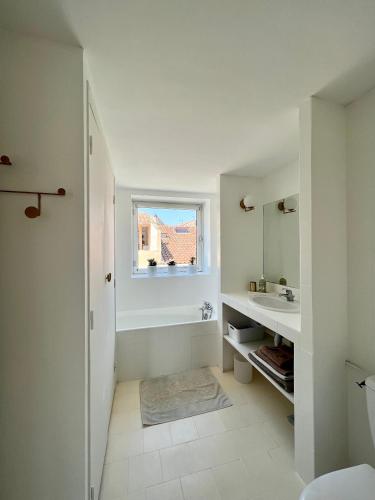 une salle de bain blanche avec un lavabo et un miroir dans l'établissement Duplex le Saint Paul, à Arles