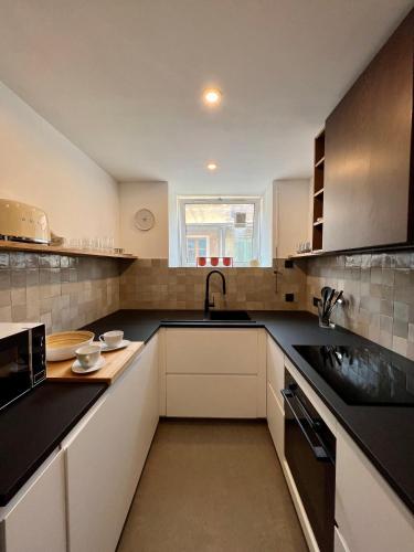 une cuisine avec des armoires blanches et des comptoirs noirs dans l'établissement Duplex le Saint Paul, à Arles