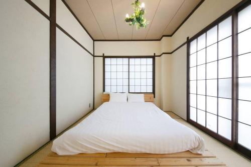a bedroom with a bed in a room with windows at ぷふか亀戸 in Tokyo