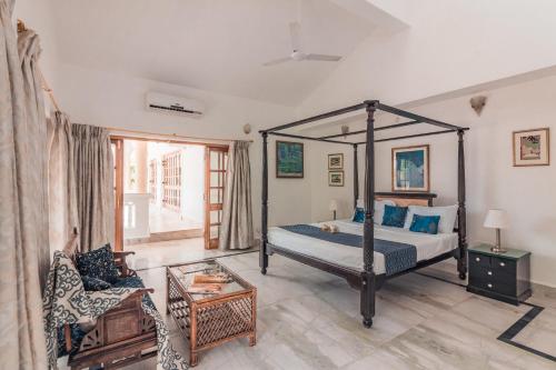 a bedroom with a canopy bed and a living room at Beachfront mansion with pool in Calangute