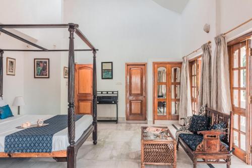 a bedroom with a canopy bed and a chair at Beachfront mansion with pool in Calangute