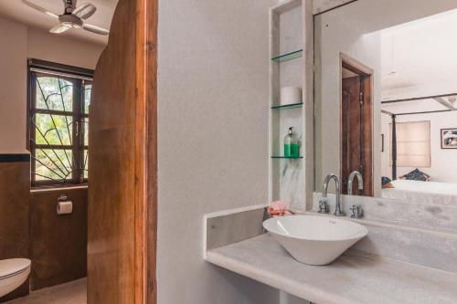 a bathroom with a sink and a toilet and a mirror at Beachfront mansion with pool in Calangute