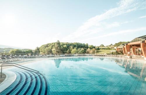 a large swimming pool with chairs in a resort at Thermalhotel Leitner in Loipersdorf bei Fürstenfeld