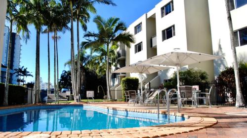 a swimming pool with chairs and umbrellas next to a building at Great Views, Ultimate Comfort and Top Location! in Caloundra