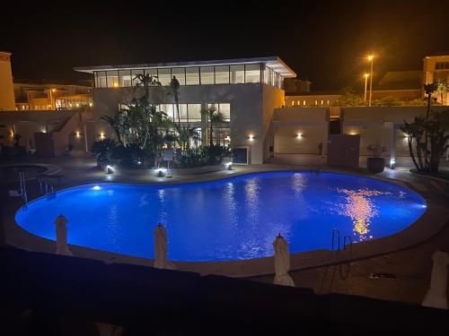 ein großer Pool vor einem Haus in der Nacht in der Unterkunft Apartamento Punta Umbría Parking Incluido y Piscina in Punta Umbría