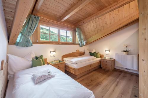 two beds in a room with wooden ceilings at Bergblick App Fichte in Villnoss