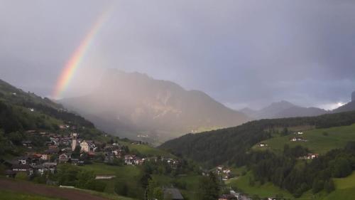 a rainbow over a small town in a valley at Bergblick App Fichte in Villnoss