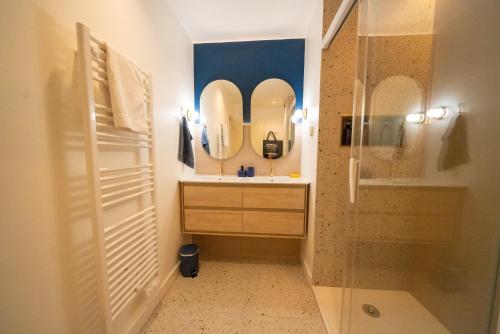 a bathroom with a sink and a shower with mirrors at Roma Divine home cinéma et jardin in Nîmes