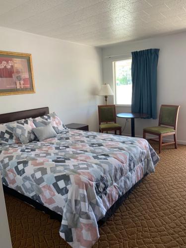 1 dormitorio con 1 cama, 2 sillas y ventana en Monticello Inn - Monticello, Indiana en Monticello