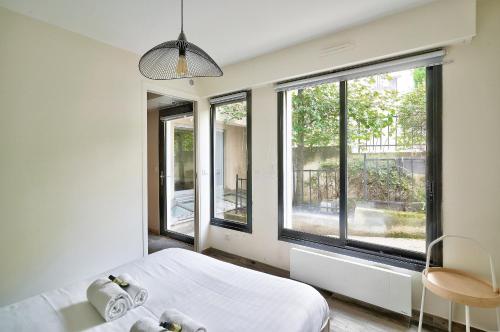 Schlafzimmer mit einem Bett und großen Fenstern in der Unterkunft Bel appartement idéal pour 4 personnes, 2 chambres in Paris