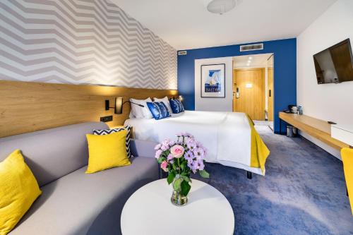 a hotel room with a bed and a couch with a vase of flowers at Best Western Hotel Jurata in Jurata