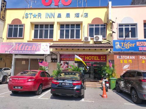 dos coches estacionados en un estacionamiento frente a un hotel en Hotel Star Inn, en Teluk Intan