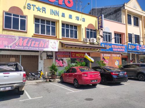 a group of cars parked in a parking lot in front of a building at Hotel Star Inn in Teluk Intan