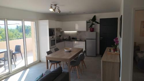 cocina y sala de estar con mesa y sillas en Les Bosquets JOLY, en Montauroux