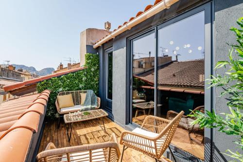 un patio con sillas y mesas en un balcón en LOFT EN VILLE - Duplex Terrasse coeur historique avec vue dégagée & Parking souterrain Offert, en La Ciotat