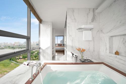 baño con bañera y ventana grande en Oakwood Hotel & Apartments Saigon, en Ho Chi Minh