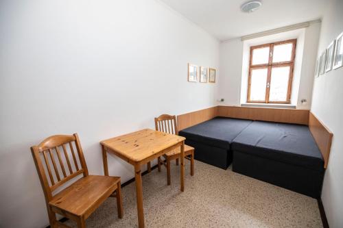 a room with a bed and a table and chairs at Hotel Praha in Broumov