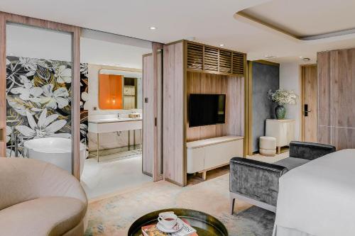 a living room with a couch and a tv in a room at Hanoi Le Jardin Hotel & Spa in Hanoi