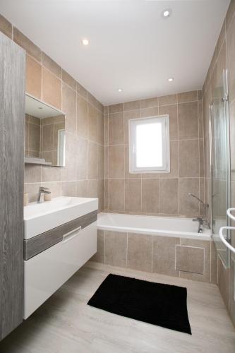 une salle de bain avec une baignoire blanche et un lavabo dans l'établissement Plain pied climatisé piscine idéalement situé, à Boulazac
