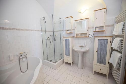a white bathroom with a shower and a sink at Hotel Praha in Broumov