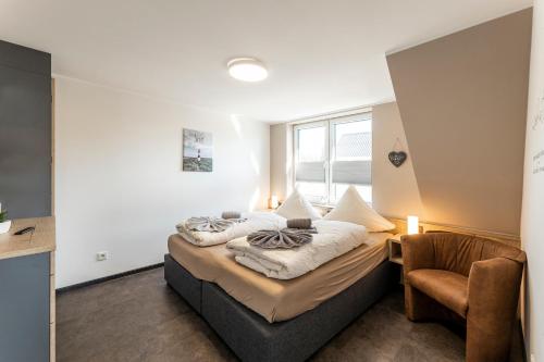 a bedroom with a bed and a chair at Sommerwind Borkum Alfonso Wohnung 3 - Urlaub mit Hund in Borkum
