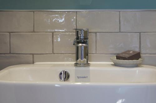 a bathroom sink with a soap dispenser and a bar of chocolate at The Grainary Boutique B&B in Scarborough