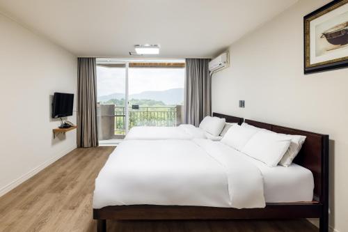 a bedroom with two beds and a large window at Kensington Resort Gyeongju in Gyeongju