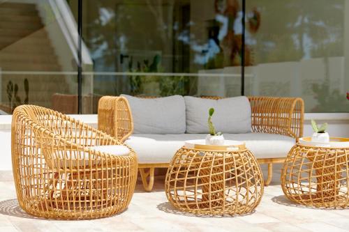 two wicker chairs and a couch on a patio at Iberostar Selection Santa Eulalia Adults-Only Ibiza in Santa Eularia des Riu